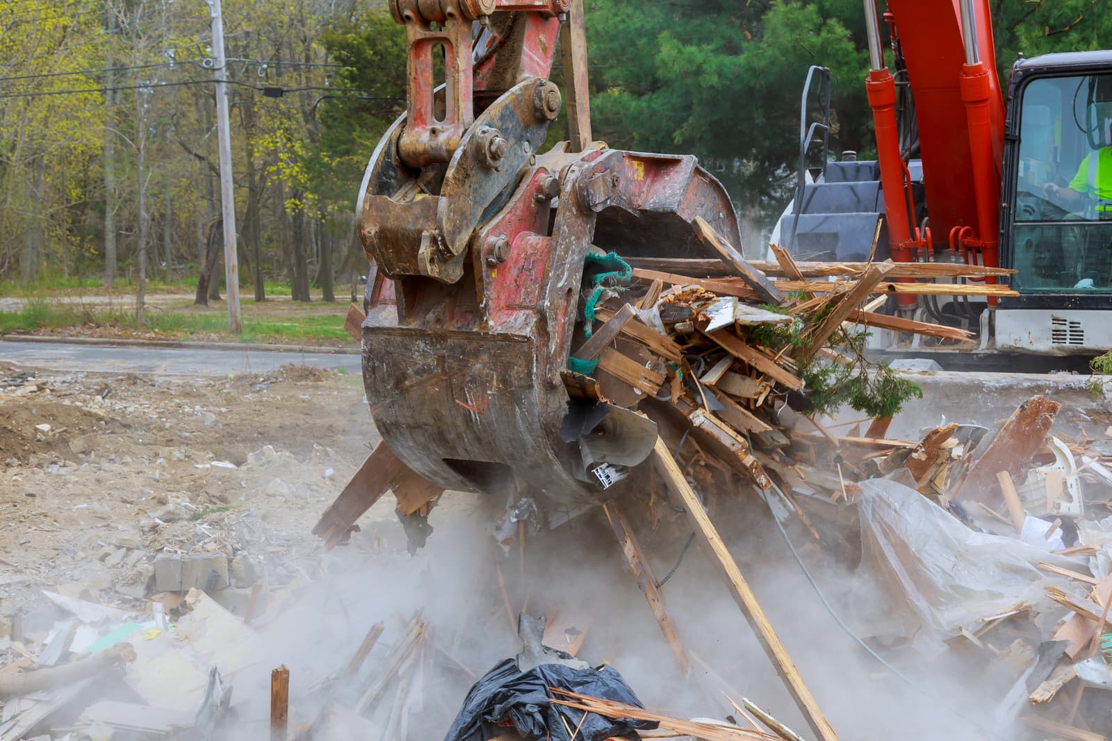 Excavator grapple sorting through demolition debris